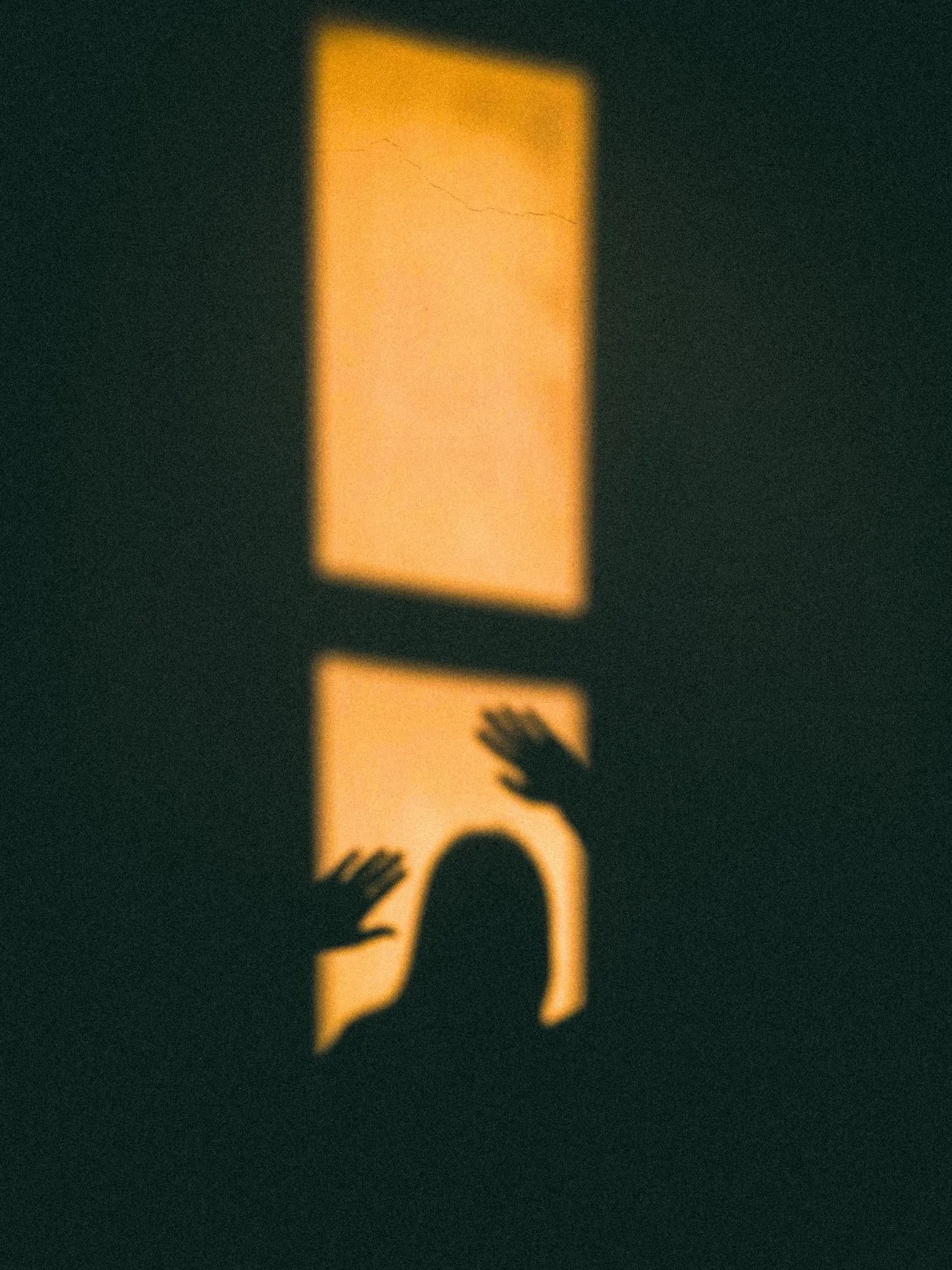 Schatten im warmen Fensterlicht auf dunkler Wand